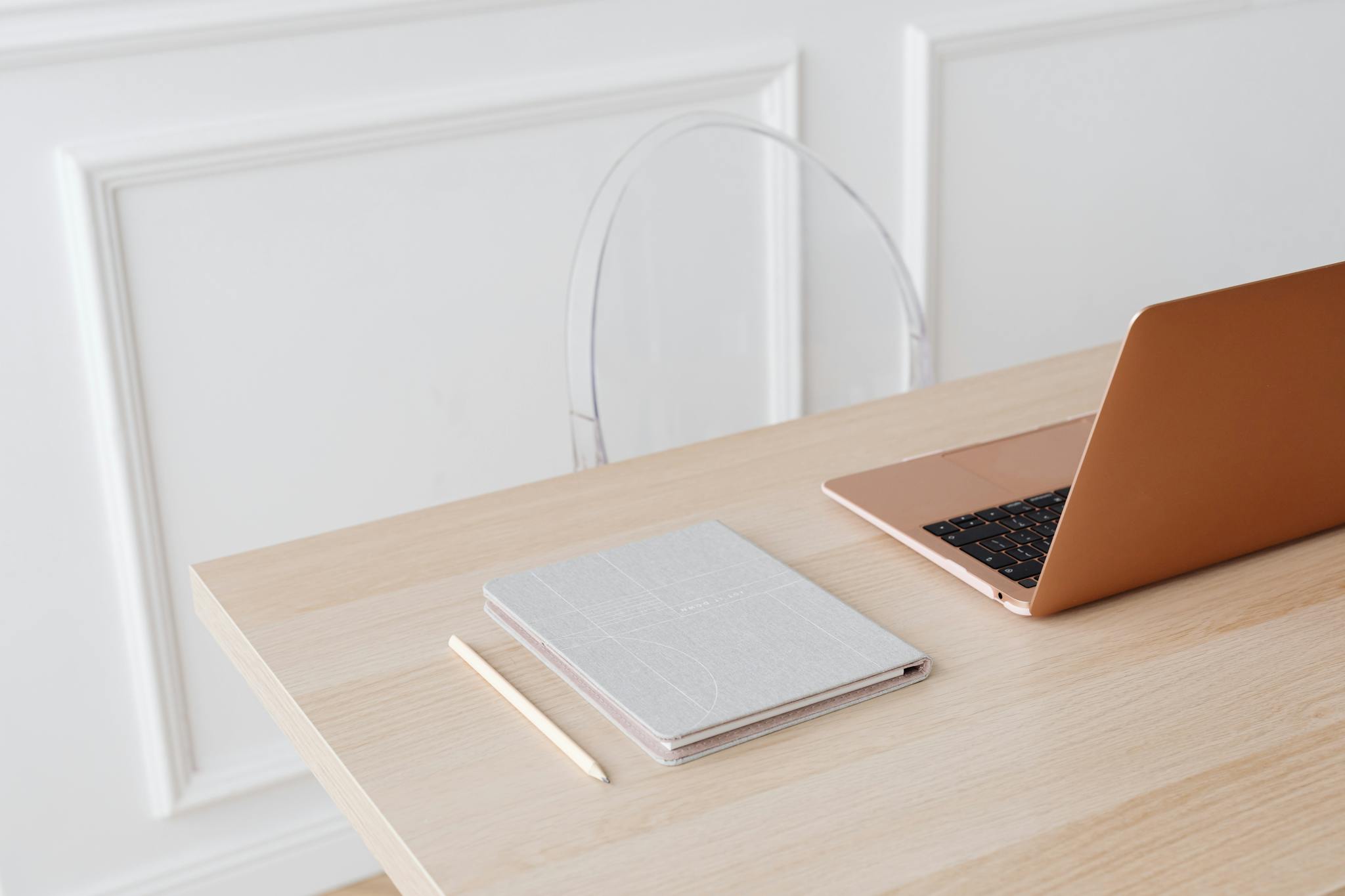 Bright, minimalist setup featuring a laptop and notebook on a wooden desk, perfect for modern workspace inspiration.